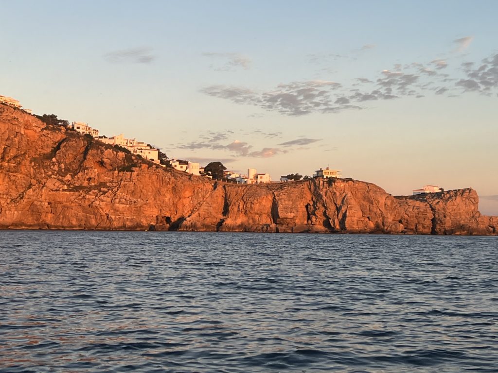 Falaises rouges éclairées par le soleil levant au-dessus de la mer