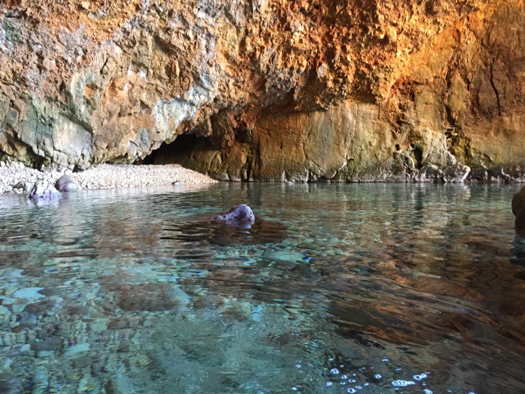 Grotte aux parois ocre au-dessus d'une eau transparente