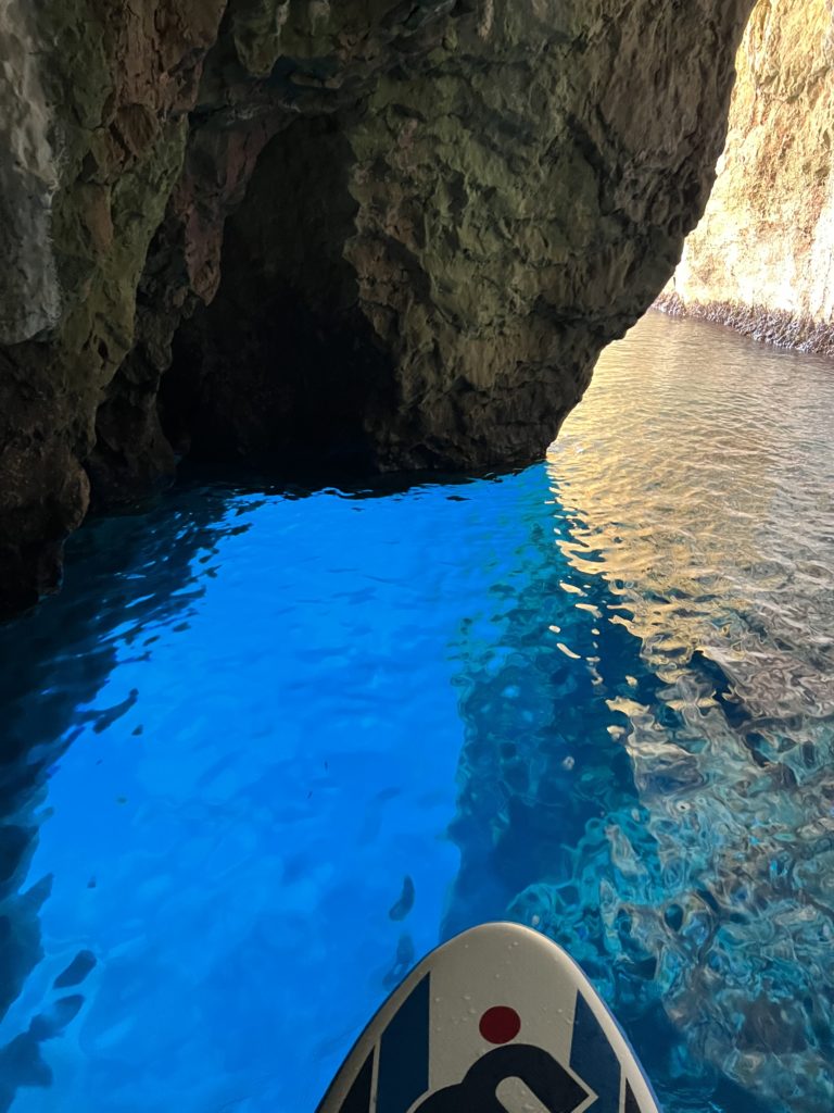 Paddle à l'entrée d'une grotte à l'eau bleu turquoise près de Cala Montgó