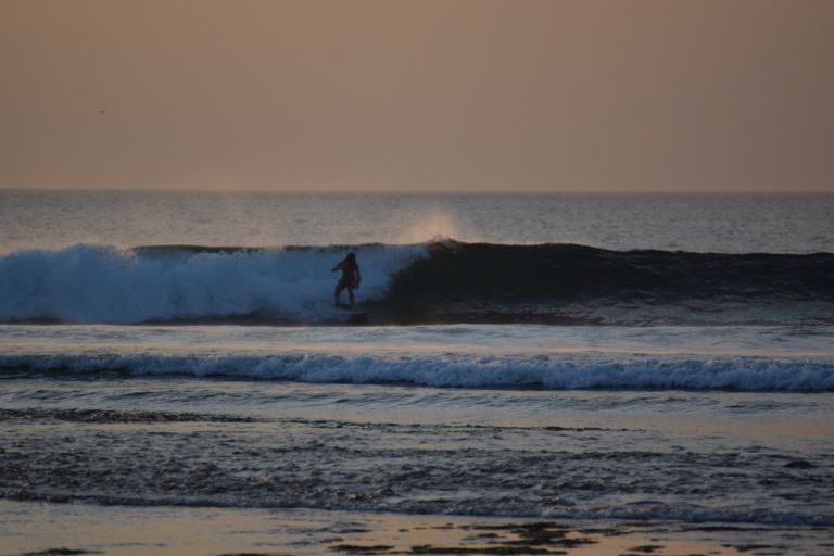 Surfeur sur une vague au coucher du soleil à Balangan