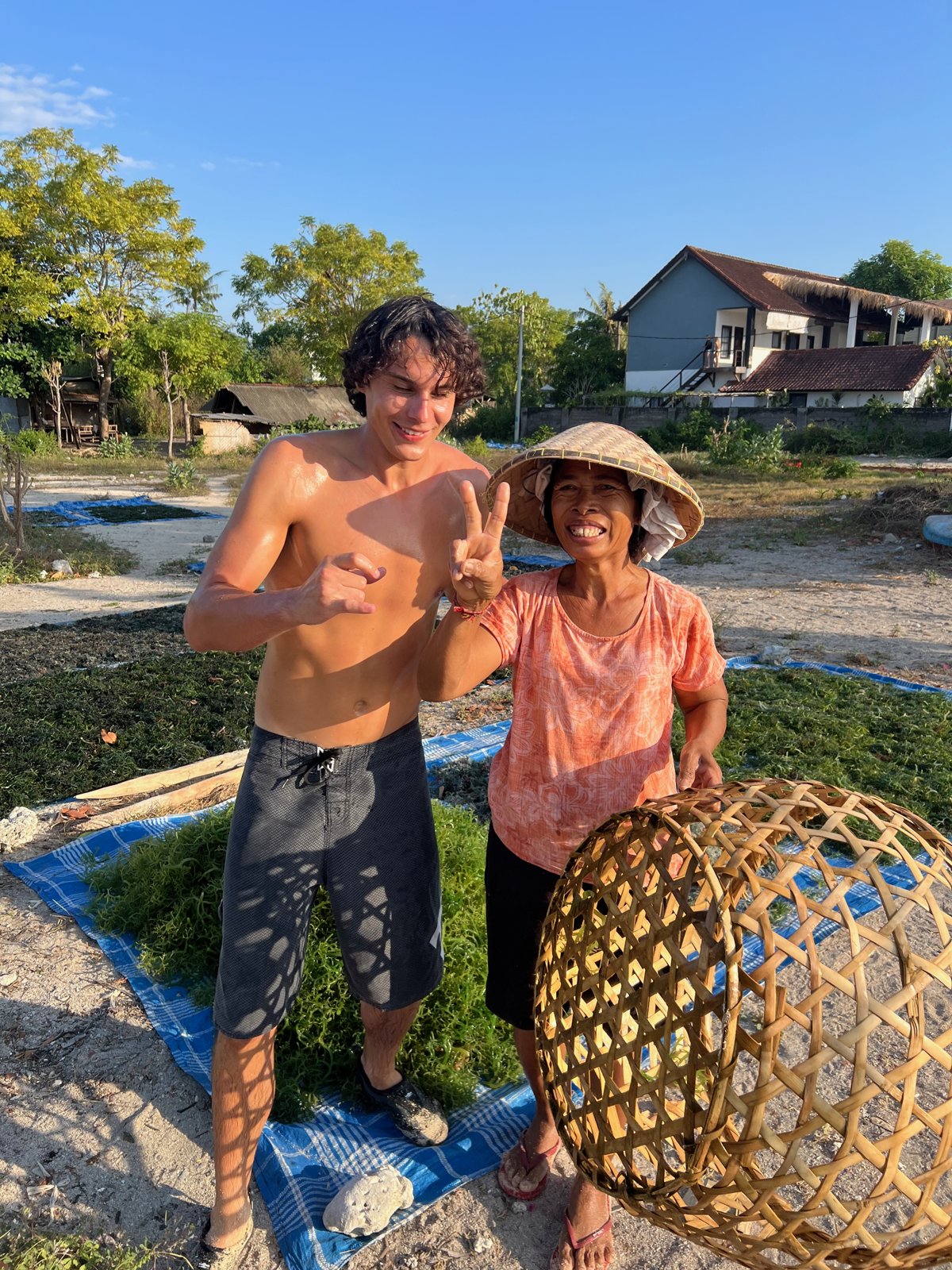Paul et la cultivatrice d'algues posent ensemble avec le panier en bambou sur la plage de Nusa Lembongan