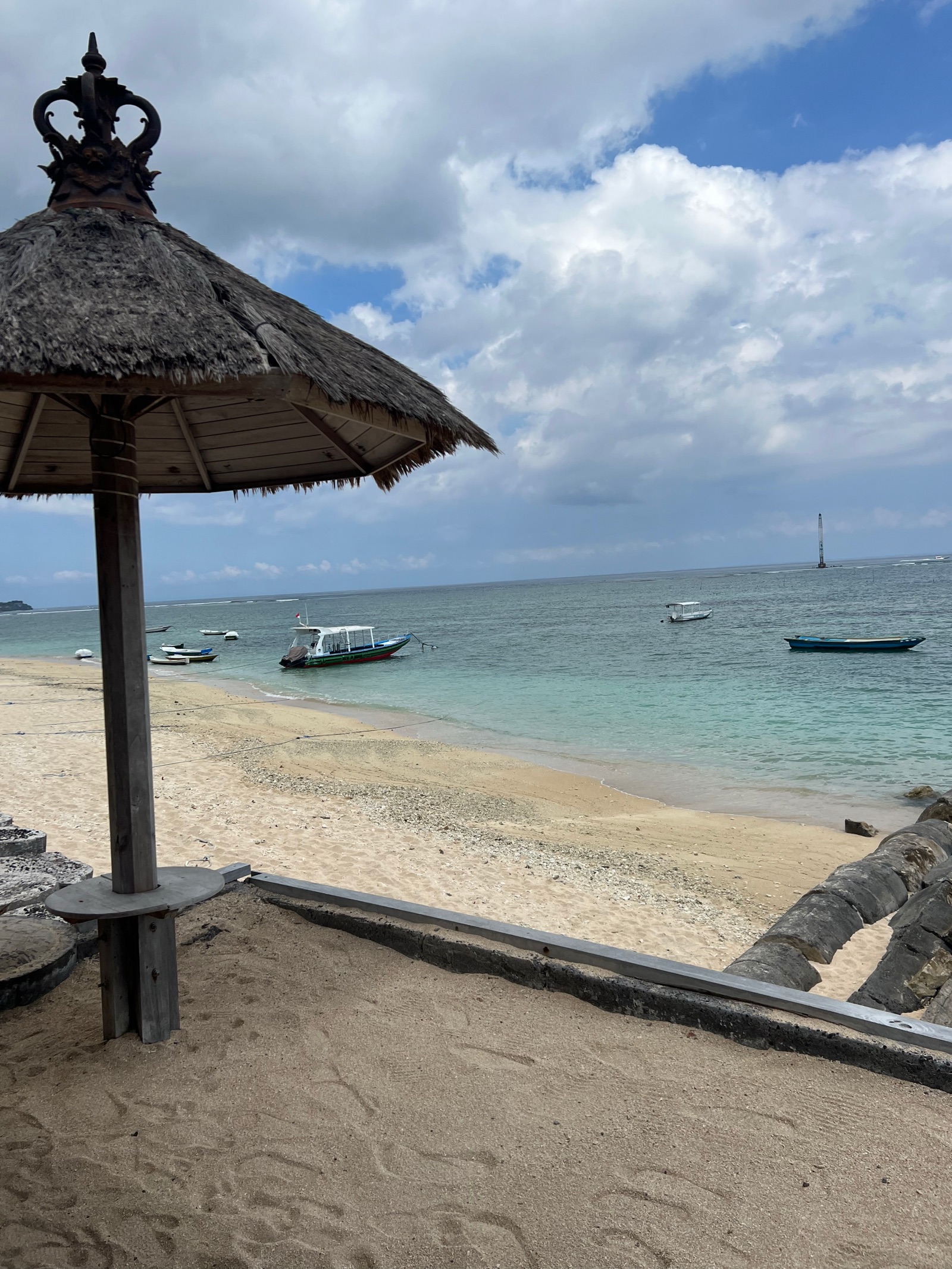 Parasol de paille sur la plage de Jungut Batu à Nusa Lembongan, bateaux au mouillage