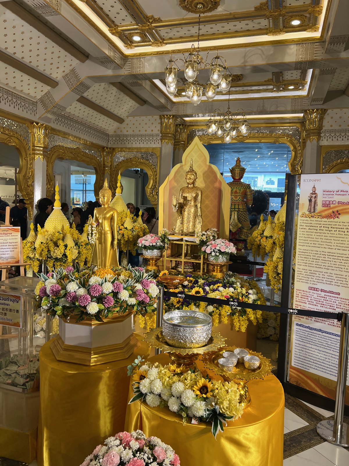 Bouddha doré entouré de fleurs dans un sanctuaire d'ICONSIAM