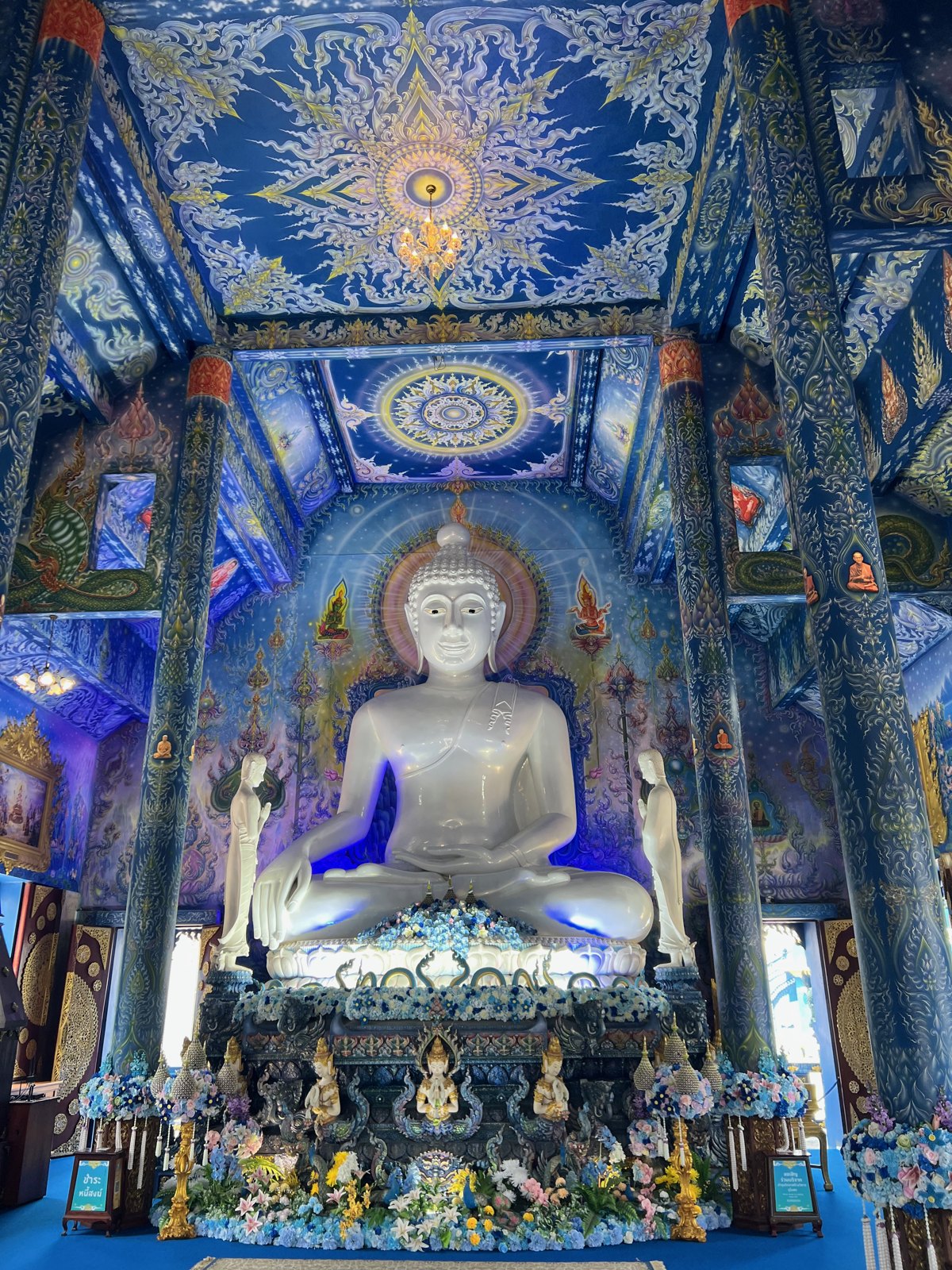 Bouddha blanc dans l'intérieur bleu et doré du Temple bleu
