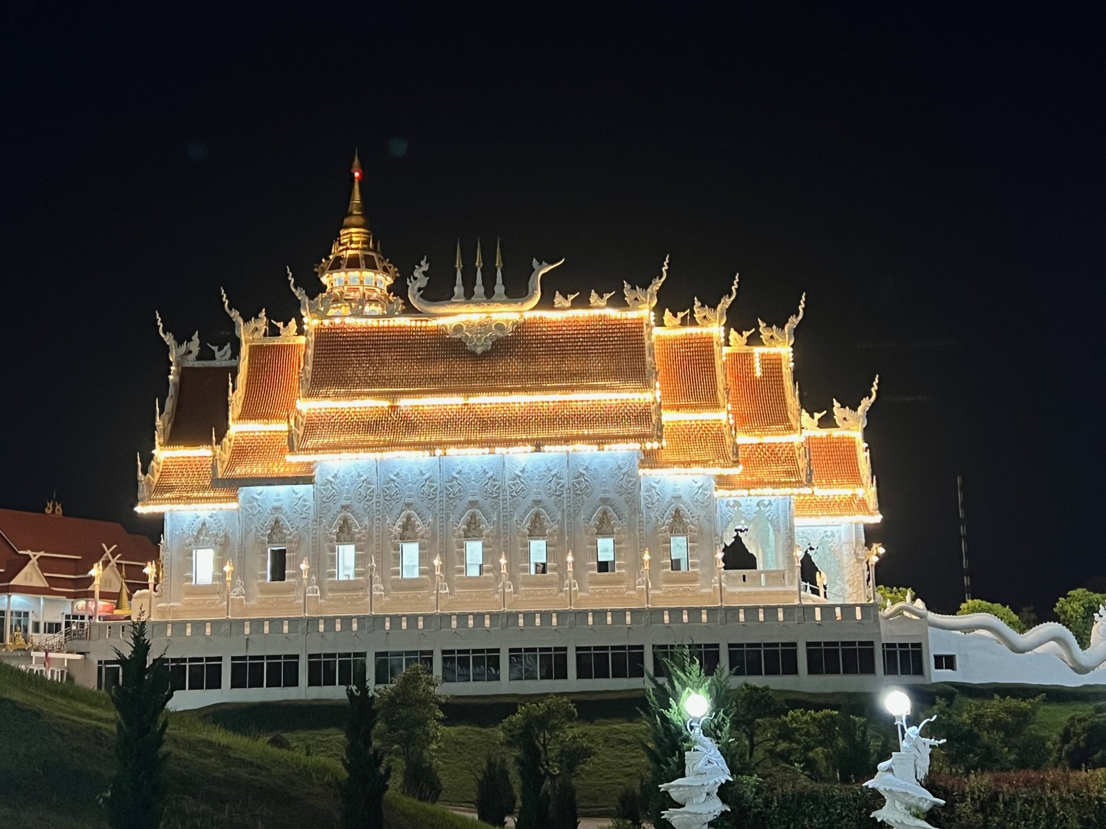 Temple blanc aux toits dorés illuminé la nuit au Wat Huay Pla Kang