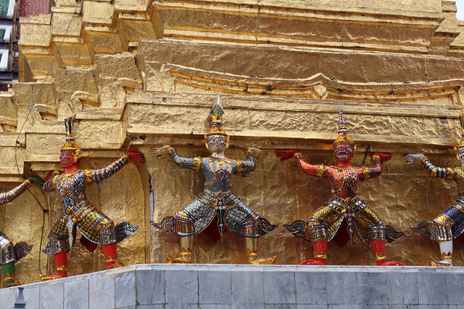 Statues de démons et de singes gardiens soutenant un chedi doré au Wat Phra Kaew