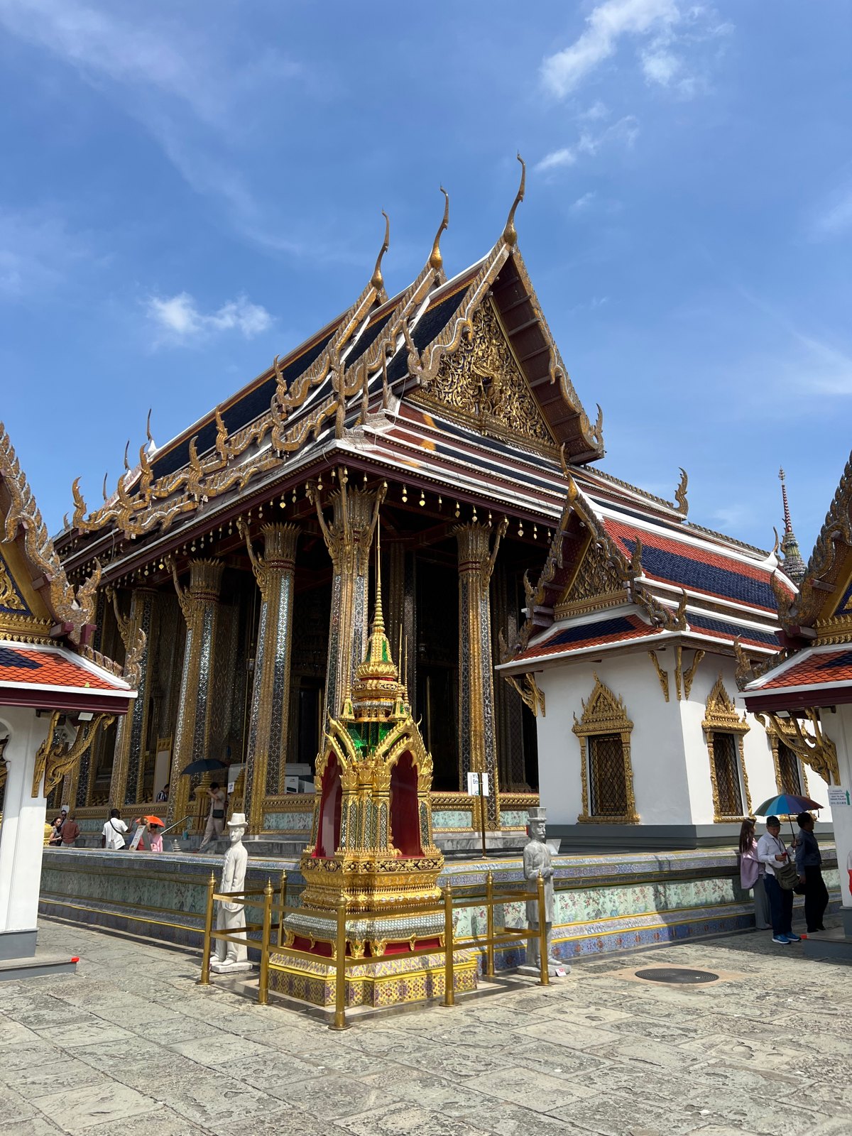 Sanctuaire aux toits rouges et dorés du Wat Phra Kaew sous un ciel bleu